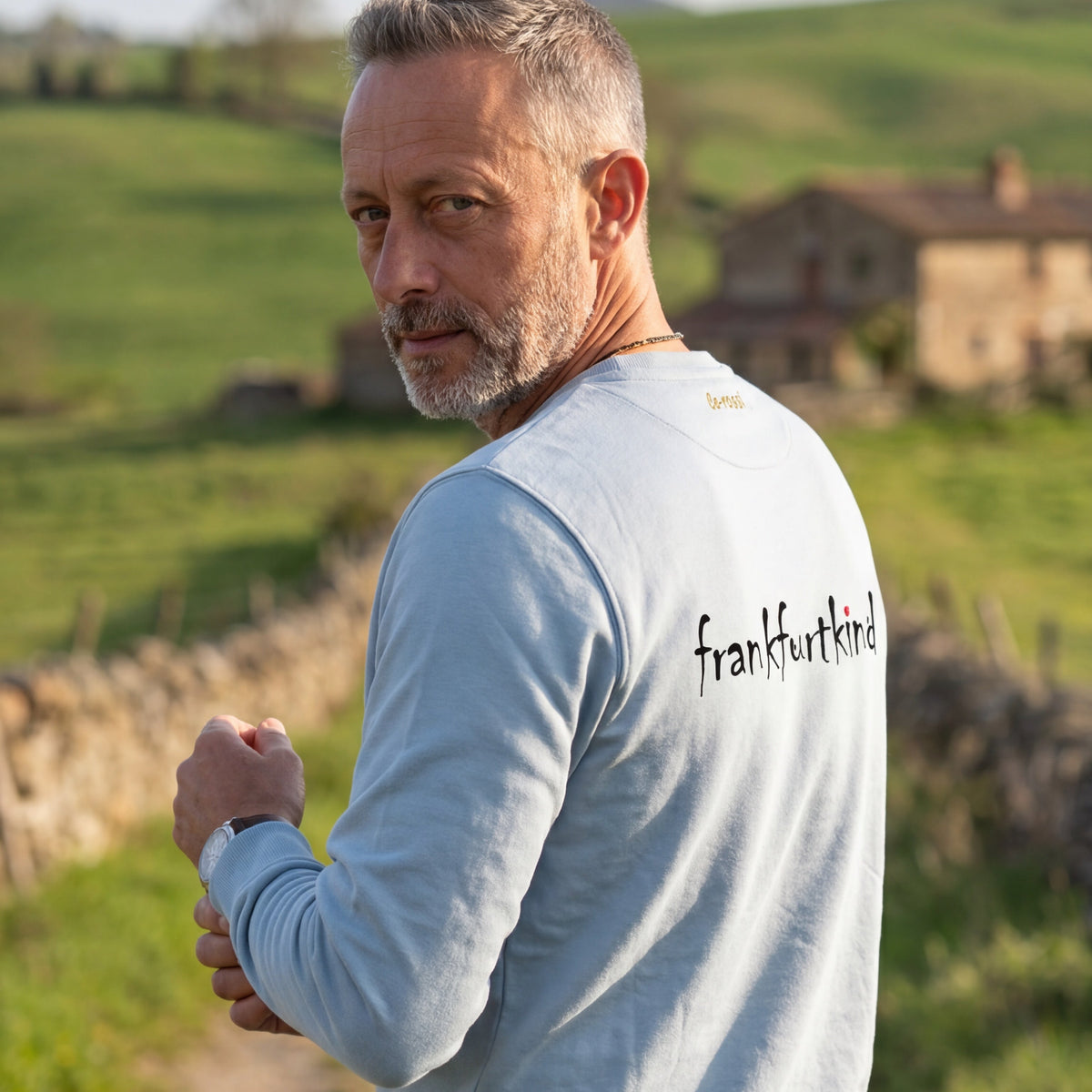 Fog-Blue Farbener Bembel und Geripptes Frankfurt organic Sweatshirt von frankfurtkind mi Rückentprint, getragen von einem männlichen Model.