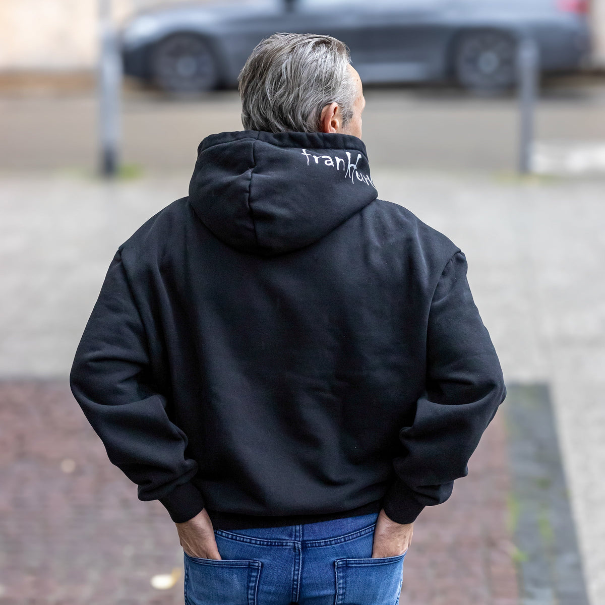 Schwarzer frankfurtkind oversized Hoodie von frankfurtkind mit Kapuzenprint, getragen von einem männlichen Model.