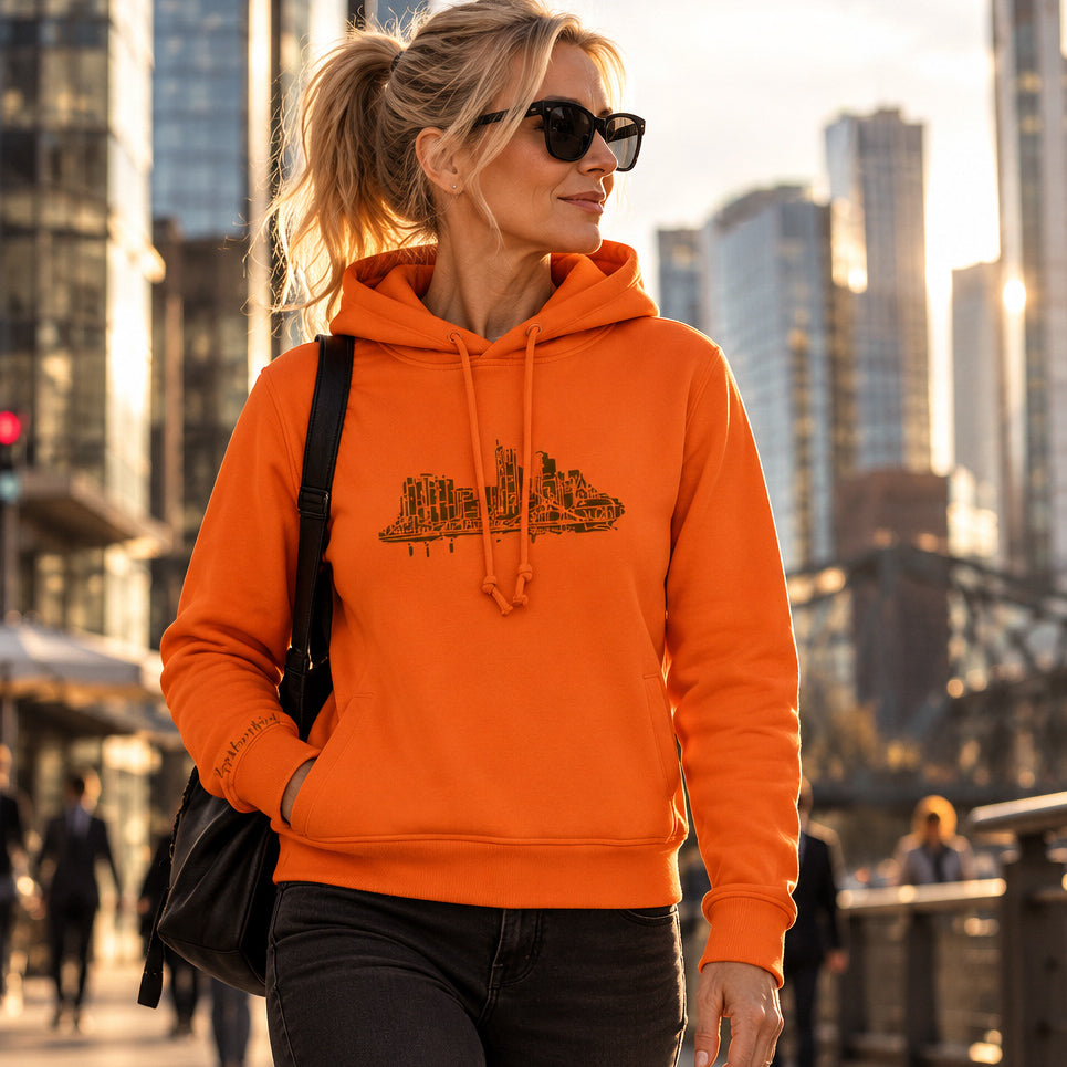 Orange Farbener Skyline Frankfurt Organic Damen Hoodie von frankfurtkind mit Frontprint, getragen von einem weiblichen Model.