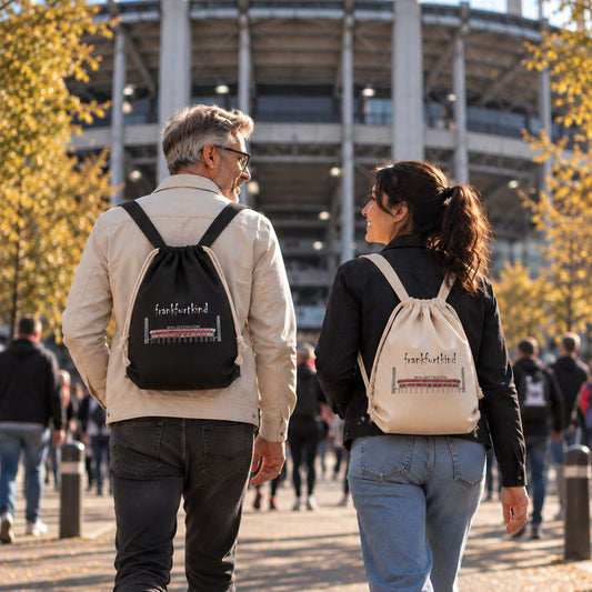 Schwarzer und natur farbener Waldstadion Frankfurt Travel Rucksack von frankfurtkind mit Print, getragen von einem weiblichen und einem männlichen Model.